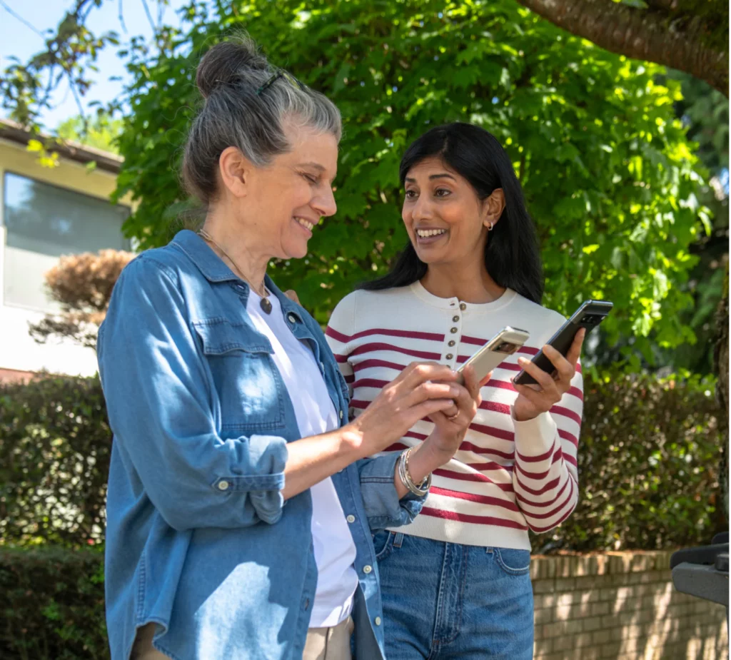 Two Neighbors Sharing their information on smart phones in front of house