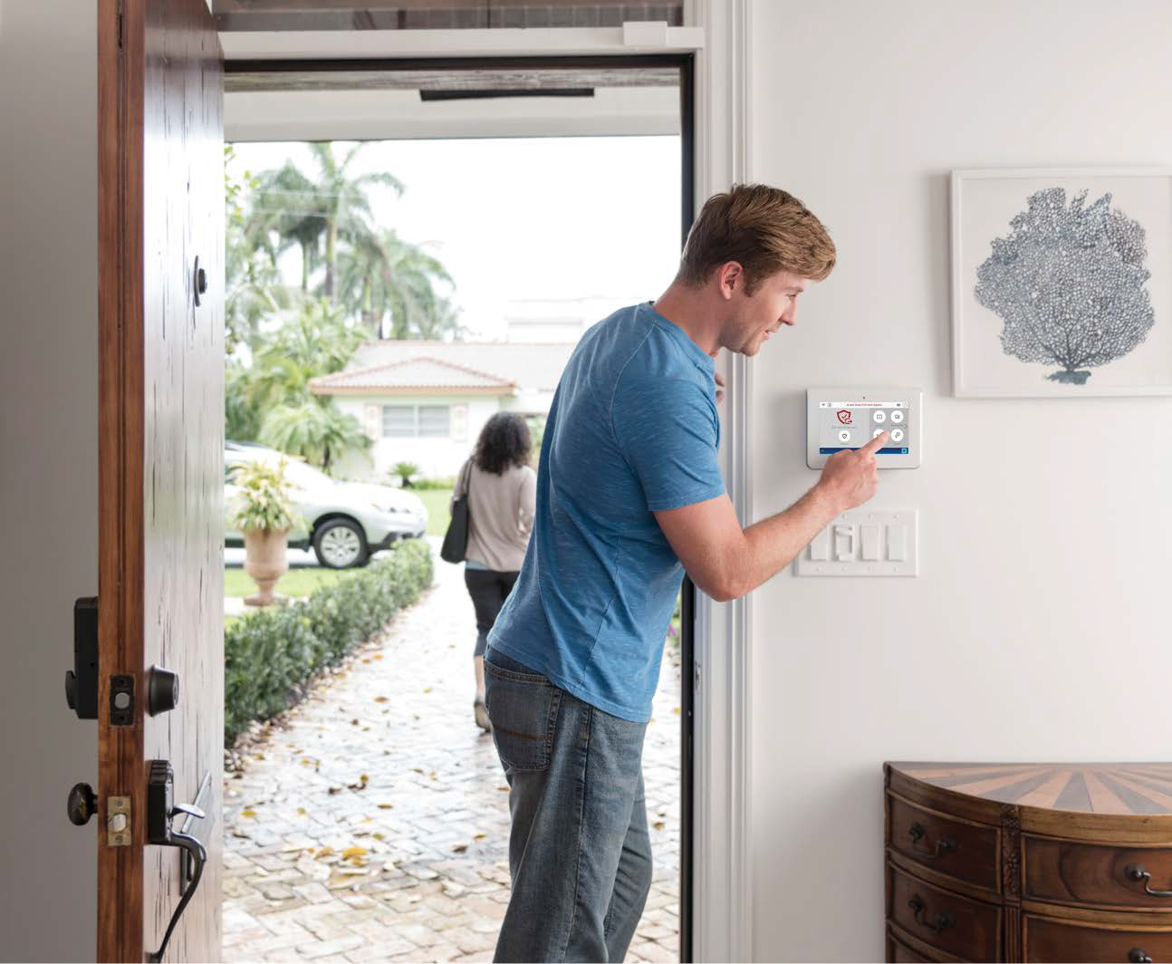 Man arming command alarm keypad before exiting home